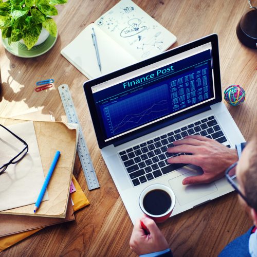 man working on laptop while holding mug